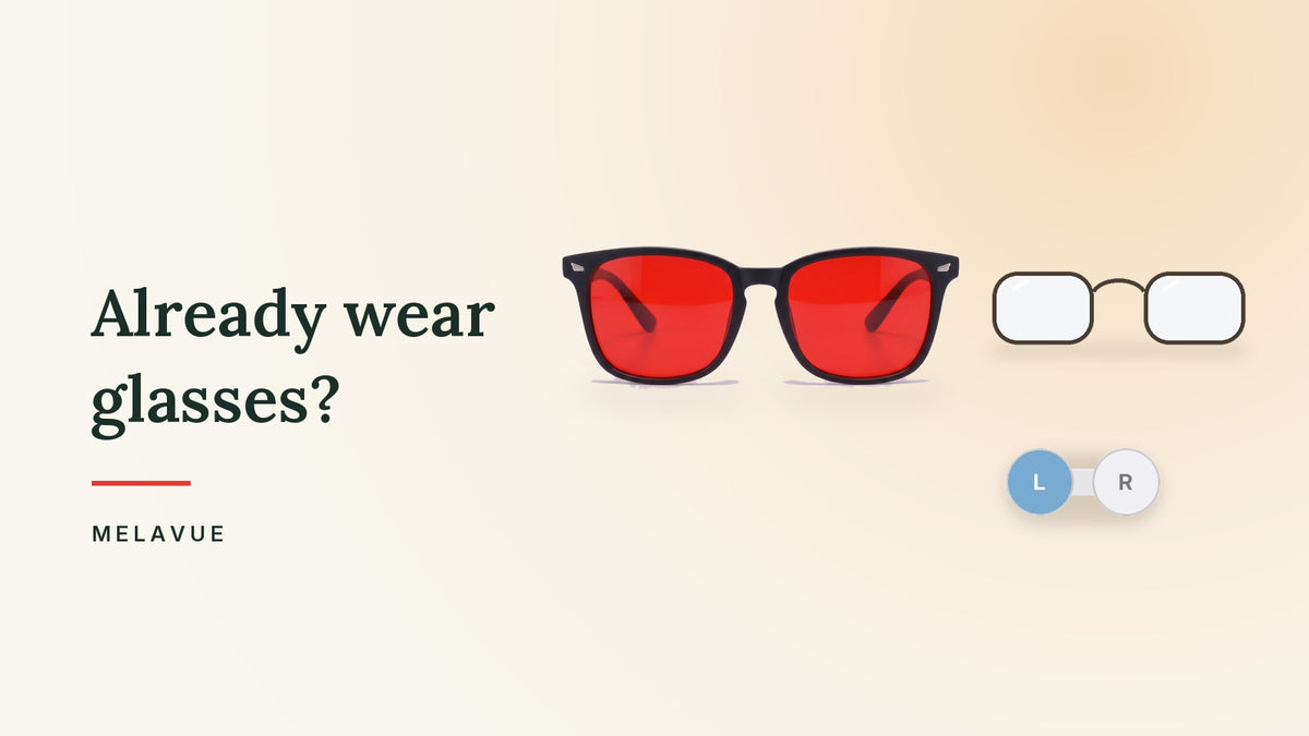 Melavue Midnight red lens glasses beside a pair of everyday prescription glasses and a contact lens case on a cream surface